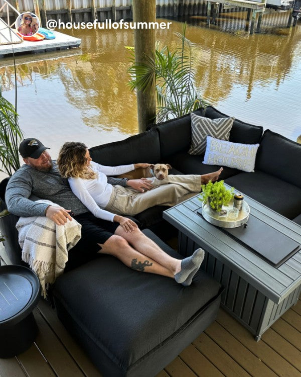 Lifestyle image of a couple and dog relaxing on a Modular Outdoor Washable 5-Seater Corner Sectional with Ottoman in Classic Canvas Charcoal, shown in a real customer outdoor setti