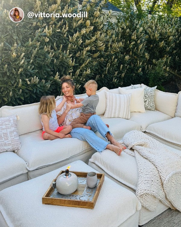 Lifestyle image of a customer and children sitting on a Modular Outdoor Washable 7-Seater Open-Ends U-Sectional with Bench Ottoman in Alfresco Boucle Creme, shown in a real photo