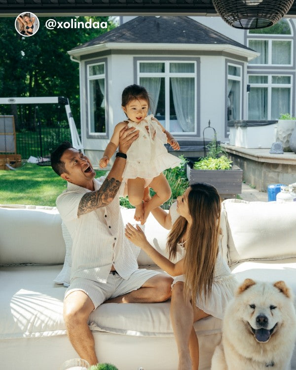 Lifestyle image of a couple and child sitting on a Modular Outdoor Washable 4-Seater Sofa and Armchair Set in Nano Slubweave Chai, shown in a real customer outdoor setting.